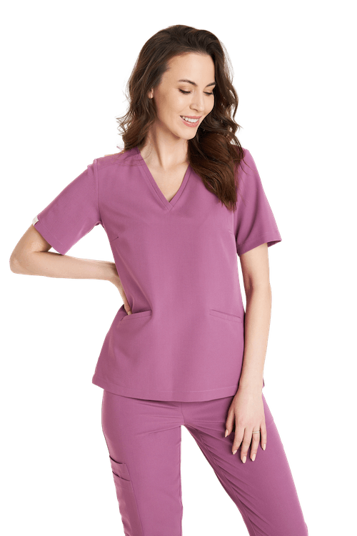 Kobieta ubrana w wygodny różowy strój medyczny na białym tle.
