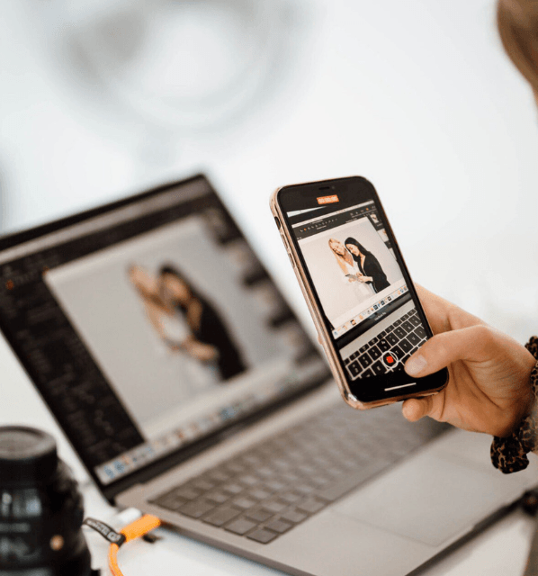 Osoba tworząca sesję zdjęciową z modelkami w odzieży medycznej na telefonie i laptopie.