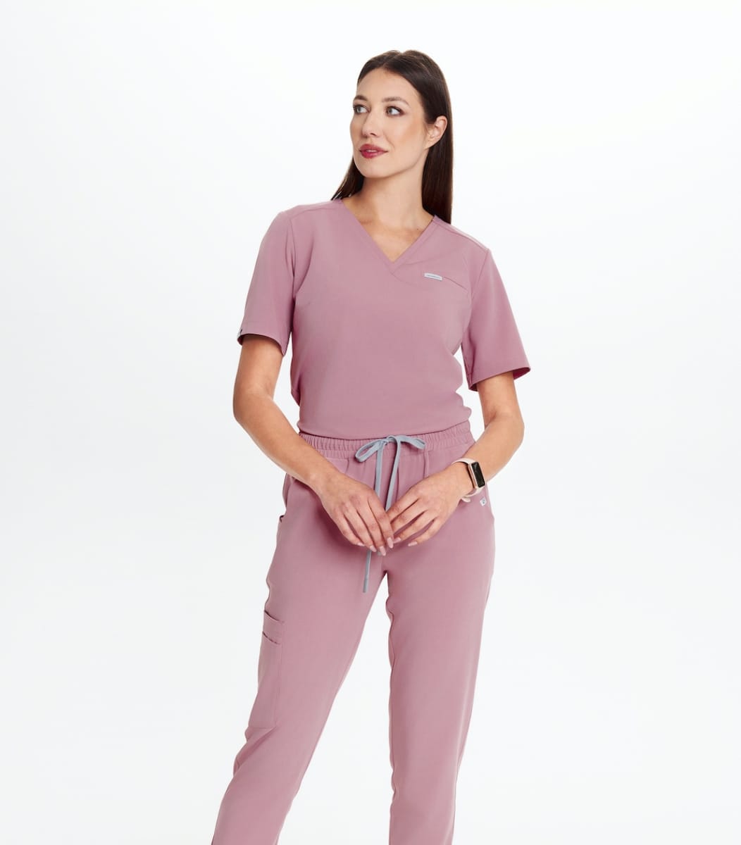 Kobieta w różowym komplecie odzieży medycznej na białym tle.